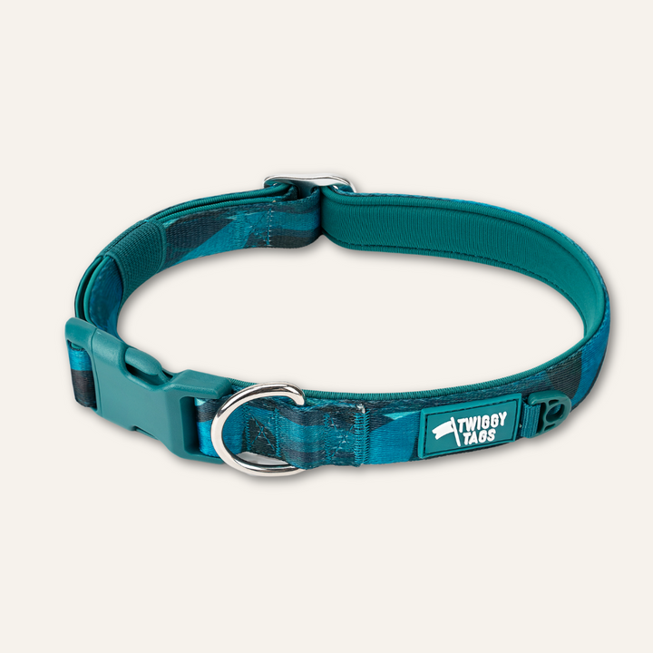 A blue dog collar with a neoprene lined design, featuring a buckle closure and a brand logo on the front.